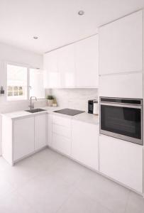 a white kitchen with white cabinets and a sink at Maison prairie en fleurs in Le Perray-en-Yvelines