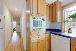 a kitchen with wooden cabinets and a microwave at Dog-Friendly Sunriver condo with deck bikes in Sunriver
