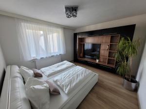 a bedroom with a white bed and a television at Ferienwohnung Birkenhügel in Schörfling