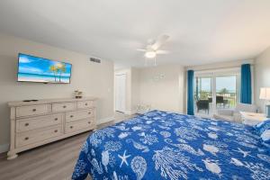 a bedroom with a blue bed and a tv at Island Beach Club #P3E in Ybel +32 photos