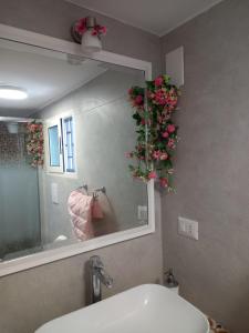 a bathroom with a mirror and a sink with flowers at La casa dei lapilli, Pompei in Terzigno