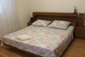 a bedroom with a bed with a floral bedspread and pillows at The Sea House Jaz in Preko