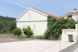 a white house with a basketball court in front of it at The Sea House Jaz in Preko