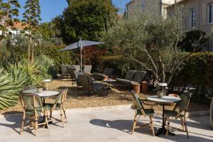 a patio with tables and chairs and an umbrella at Hotel Verlaine in Cannes