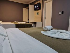 a hotel room with a bed and a tv on the wall at Pousada Nosso Lar - Opte sem ou com Café, Estacionamento e a uma Quadra da Praia in Guarujá