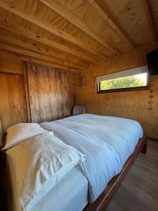 a bed in a wooden room with a window at CasaAndina in Malalcahuello