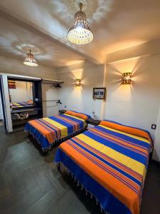Zwei Betten stehen in einem Zimmer mit zwei Lampen. in der Unterkunft Hotel Yubazuu in San Pablo Villa de Mitla