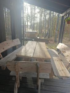 a wooden table and benches on a porch at Dom U Piepki in Zdunowice Małe