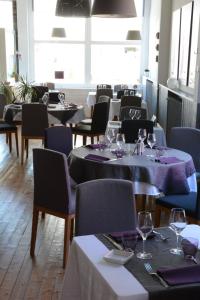 une salle à manger avec des tables, des chaises et des verres à vin dans l'établissement Logis Le Petit Trianon, à Saint-Brévin-les-Pins