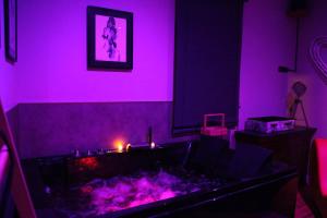 a purple room with a bathtub with purple lighting at Secret Balnéo in Floirac