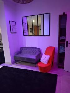 a purple living room with a couch and a red chair at Secret Balnéo in Floirac