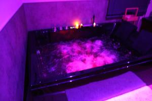 a hot tub in a room with purple lighting at Secret Balnéo in Floirac +2 photos