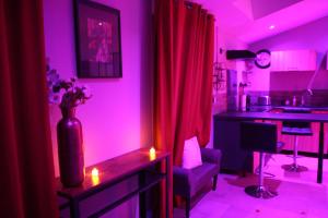 a living room with purple lighting and a kitchen with a table at Secret Balnéo in Floirac