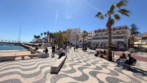 people sitting on benches on a sidewalk next to the beach at Cozy one bedroom apartment in the heart of Cascais historic center in Cascais