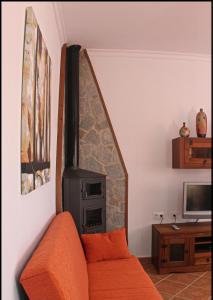 sala de estar con sofá naranja y chimenea en Chalet Vigía 113, en Conil de la Frontera