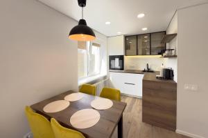 a kitchen and dining room with a wooden table and yellow chairs at AC Vienibas Square apartments in Daugavpils
