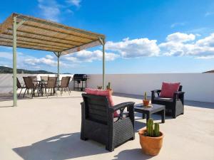 a patio with chairs and tables on a roof at Villa Anafoufou Afionas with private heatable pool in Afionas