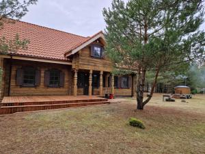 a log cabin with a tree in front of it at Sodyba Vovierių slėnis in Kuras