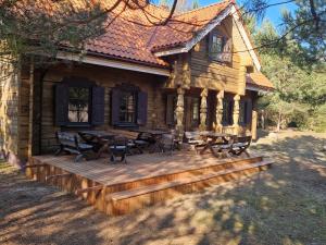 a log cabin with tables and chairs on a deck at Sodyba Vovierių slėnis in Kuras
