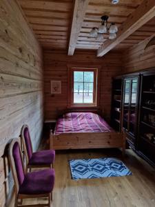 a bedroom with a bed and two chairs in a cabin at Sodyba Vovierių slėnis in Kuras +11 photos