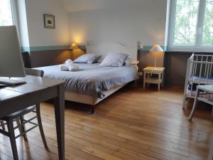 a bedroom with a bed and a desk with a desk at Gîtes Les Clairets - Normandie in Mortain