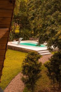 a swimming pool in a yard with chairs and trees at Cabanas Malacara in Praia Grande