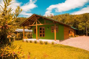 a green tiny house in a yard at Cabanas Malacara in Praia Grande