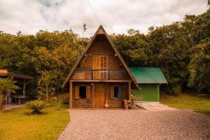 a small wooden house with a green roof at Cabanas Malacara in Praia Grande