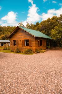 a wooden house with a green roof on a gravel road at Cabanas Malacara in Praia Grande