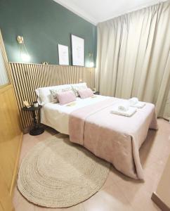 a bedroom with a large bed with white sheets and pink pillows at Plaza de la Torre in Pontevedra