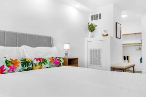 a white bedroom with a large bed with colorful pillows at Renovated Beach Front Condo TOG 310 in Panama City Beach +16 photos
