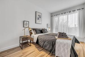 a white bedroom with a bed and a window at Initial Artsy Québec in Quebec City