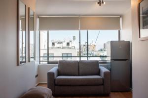 a living room with a chair and a large window at Apart Hotel Plaza Centro in El Cerrillo