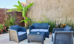 a patio with blue chairs and a table and a fence at Gîtes Arvor et Tevenn in Saint-Brevin-les-Pins