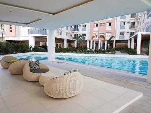 a swimming pool with a row of wicker chairs next to a building at Cozy unit in mivesa garden residence in Cebu City
