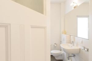 a white bathroom with a toilet and a sink at Hotel INNsel26 in Oberhausen +6 photos