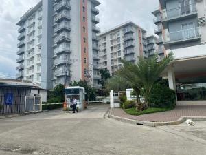 a person standing in a parking lot next to tall buildings at Cozy unit in mivesa garden residence in Cebu City