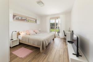 a white bedroom with a bed and a television at Fine Stay Apartments in Žirovnica