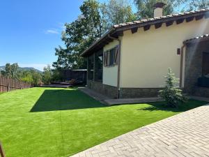 a yard with green grass next to a house at Can Roura in Rocabruna
