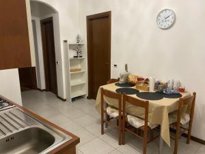 a kitchen with a table with chairs and a clock on the wall at Matì 2 con navetta 25Eur in Lonate Pozzolo