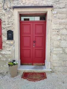 a red door on a stone building with a window at La Casa dei Ricordi in Igne