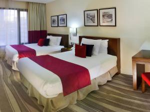 a hotel room with two beds with red pillows at Novotel Suites Riyadh Olaya in Riyadh