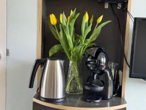 a vase with yellow flowers in it on a shelf at Hotelhuisjes Oosterleek in Oosterleek