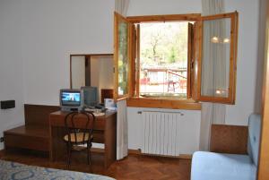 a room with a desk with a computer and a window at Hotel Archimede in Reggello