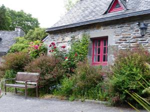 un banco frente a una casa de piedra con una ventana roja en Moulin De Beuzidou en Saint-Urbain