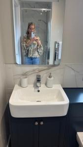 a woman taking a picture of a bathroom sink at Jack & Jill Inn Pub in Hassocks