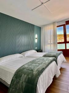 two large beds in a bedroom with a window at GH Beiramar in Cee