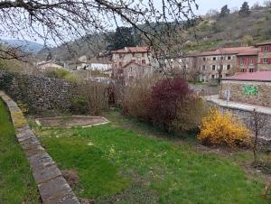 a garden with a stone wall and grass and buildings at Les Lavandières in Satillieu