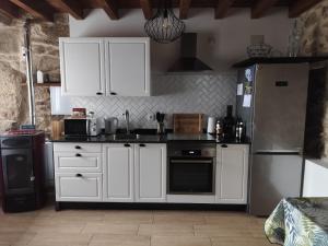 a kitchen with white cabinets and a refrigerator at Casa Mitola in Congostro