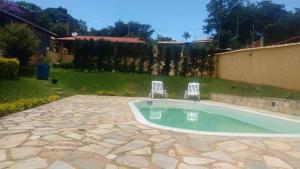 two chairs sitting next to a pool in a yard at Sossego e Lazer na Serra do Cipó, piscina e Rio in Jaboticatubas